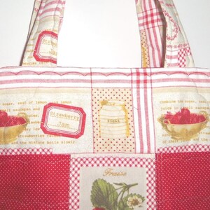 May include: A quilted tote bag featuring a patchwork design with red and white gingham, polka dots, and cream fabric panels. The print includes illustrations of strawberries in bowls, sugar jars, and text reading Strawberry Jam and Fraise.