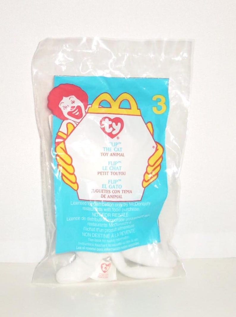 May include: A sealed clear plastic bag containing a Ty Flip the Cat toy. The packaging features a light blue background, a yellow McDonald's arch logo, the number 3, and an illustration of Ronald McDonald. Text includes Flip the Cat Toy Animal.
