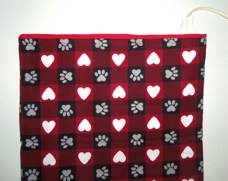 May include: Red and white checkered fabric with a pattern of paw prints and hearts. The fabric has a red border.