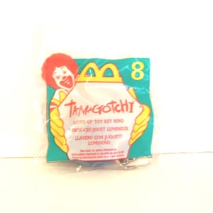 Puede incluir: Una bolsa de pl&aacute;stico sellada que contiene un llavero de juguete luminoso Tamagotchi. El empaque presenta un gr&aacute;fico de Ronald McDonald, el n&uacute;mero 8 y el texto Tamagotchi, Light-Up Toy Key Ring, Porte-Cl&eacute;/Jouet Lumineux y Llavero Con Juguete Luminoso.