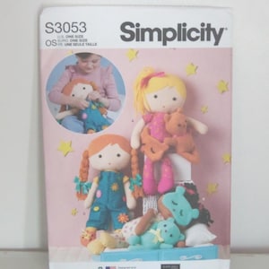 May include: Simplicity sewing pattern S3053 featuring doll designs. The cover shows several handmade dolls with various hairstyles and outfits, including a doll with pigtails and a doll with a yellow bow. The background is pink with yellow star accents.