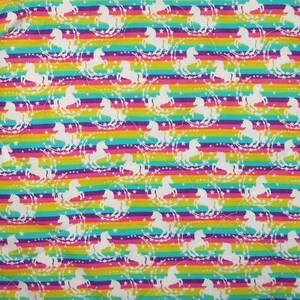 May include: A fabric featuring a repeating pattern of white unicorn silhouettes surrounded by circular star motifs. The background consists of horizontal stripes in vibrant shades of red, orange, yellow, green, blue, and purple.