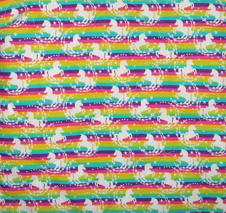 May include: A fabric featuring a repeating pattern of white unicorn silhouettes surrounded by circular star motifs. The background consists of horizontal stripes in vibrant shades of red, orange, yellow, green, blue, and purple.