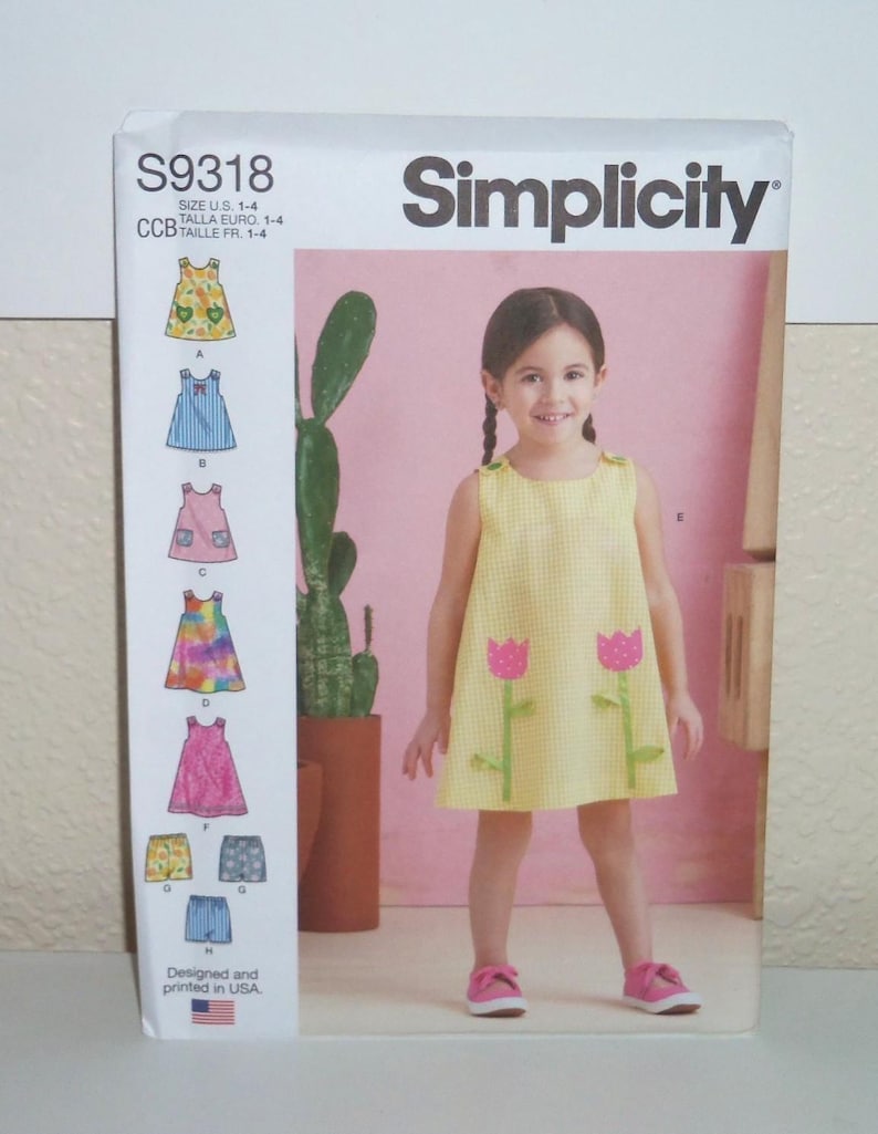 May include: A Simplicity sewing pattern envelope S9318 for sizes 1-4. The front shows a yellow gingham sleeveless dress with pink tulip appliqu&eacute;s. The left side displays illustrations of eight different dress and shorts variations with labels A through H.