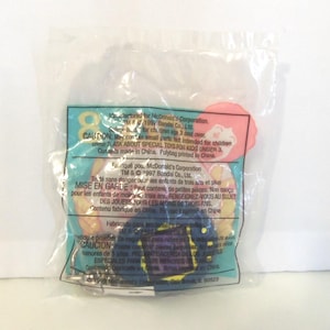 Puede incluir: Una bolsa de pl&aacute;stico transparente sellada que contiene un juguete promocional de McDonald's de 1997 de Bandai. El empaque presenta texto impreso en ingl&eacute;s, franc&eacute;s y espa&ntilde;ol, incluyendo advertencias de seguridad e informaci&oacute;n de fabricaci&oacute;n.