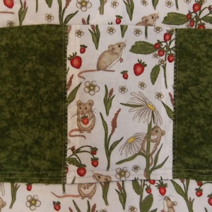May include: A fabric item featuring a central panel of white cloth with a repeating pattern of brown mice, red strawberries, and white flowers, flanked by two solid dark green textured fabric panels with visible horizontal stitching.