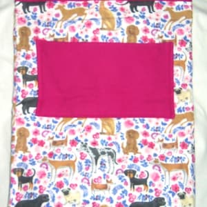 May include: A white fleece blanket with a pink fleece lining. The blanket features a repeating pattern of dogs and flowers.