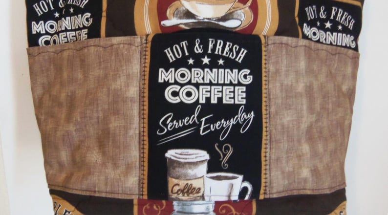 Puede incluir: Un bolso de tela acolchada con un esquema de color marr&oacute;n y negro y gr&aacute;ficos de caf&eacute;. El texto dice HOT & FRESH MORNING COFFEE SERVED EVERYDAY. El dise&ntilde;o incluye ilustraciones de tazas de caf&eacute; sobre un fondo con textura.