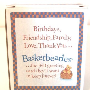 May include: A white box with a blue and orange checkered border. The text reads "Birthdays, Friendship, Family, Love, Thank You... Basketbearies...the 3-D greeting card they'll want to keep forever!" A small illustration of a teddy bear in a basket is also present.