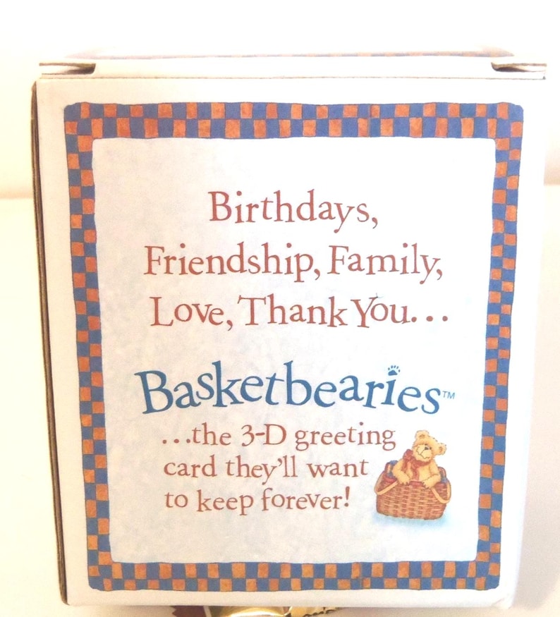 May include: A white box with a blue and orange checkered border. The text reads "Birthdays, Friendship, Family, Love, Thank You... Basketbearies...the 3-D greeting card they'll want to keep forever!" A small illustration of a teddy bear in a basket is also present.