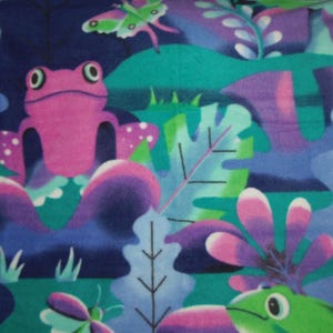 May include: A vibrant fabric design showcasing a pink frog, green frog, and butterflies set amongst stylized foliage. The pattern incorporates shades of blue, green, purple, and pink, creating a lively and playful aesthetic. Suitable for various craft projects.