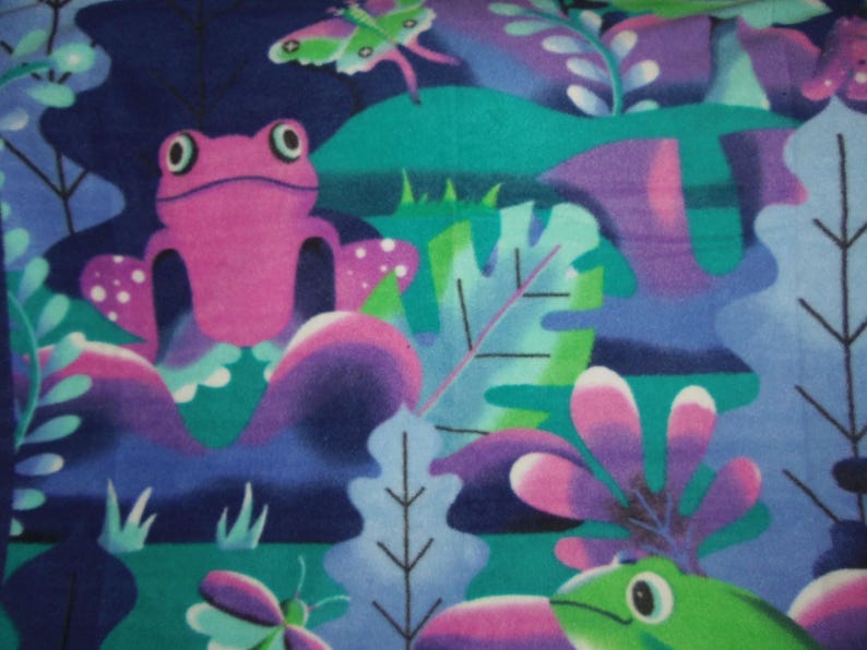 May include: A vibrant fabric design showcasing a pink frog, green frog, and butterflies set amongst stylized foliage. The pattern incorporates shades of blue, green, purple, and pink, creating a lively and playful aesthetic. Suitable for various craft projects.