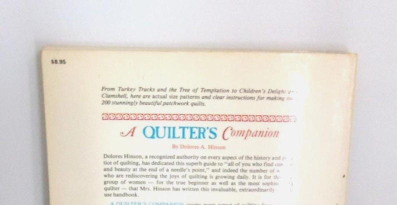 Puede incluir: Un libro de tapa blanda titulado A Quilter's Companion de Dolores A. Hinson. La cubierta es de color blanco roto con texto en rojo y azul. Presenta un borde decorativo rojo y menciona 200 patrones de patchwork. El precio 8,95 $ est&aacute; impreso.