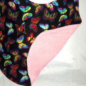May include: A black bib with a colorful butterfly pattern on one side and a pink terry cloth backing on the other side.