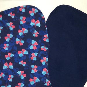 May include: Two fabric squares, one with a blue background and a pattern of pink and blue butterflies, the other a solid dark blue.