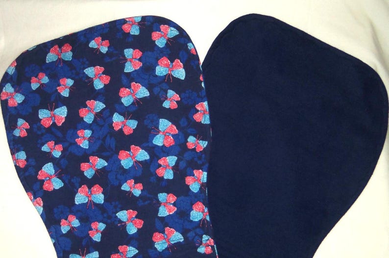 May include: Two fabric squares, one with a blue background and a pattern of pink and blue butterflies, the other a solid dark blue.