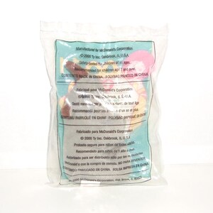 May include: A small plush toy sealed inside a clear plastic bag. The packaging features printed text in English, French, and Spanish, including McDonald's Corporation branding, the year 2000, and safety information for children aged one and over.
