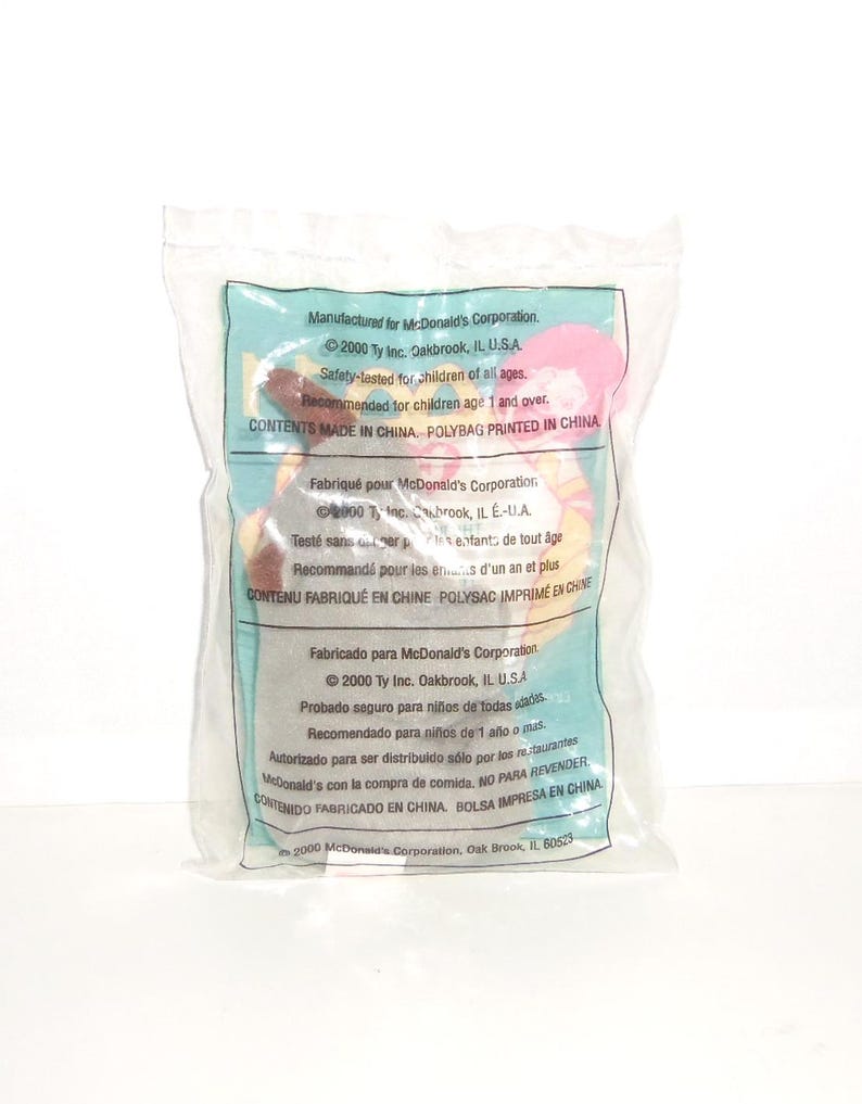 May include: A small plush toy sealed inside a clear plastic bag. The packaging features printed text in English, French, and Spanish, including McDonald's Corporation branding, the year 2000, and safety information for children aged one and over.