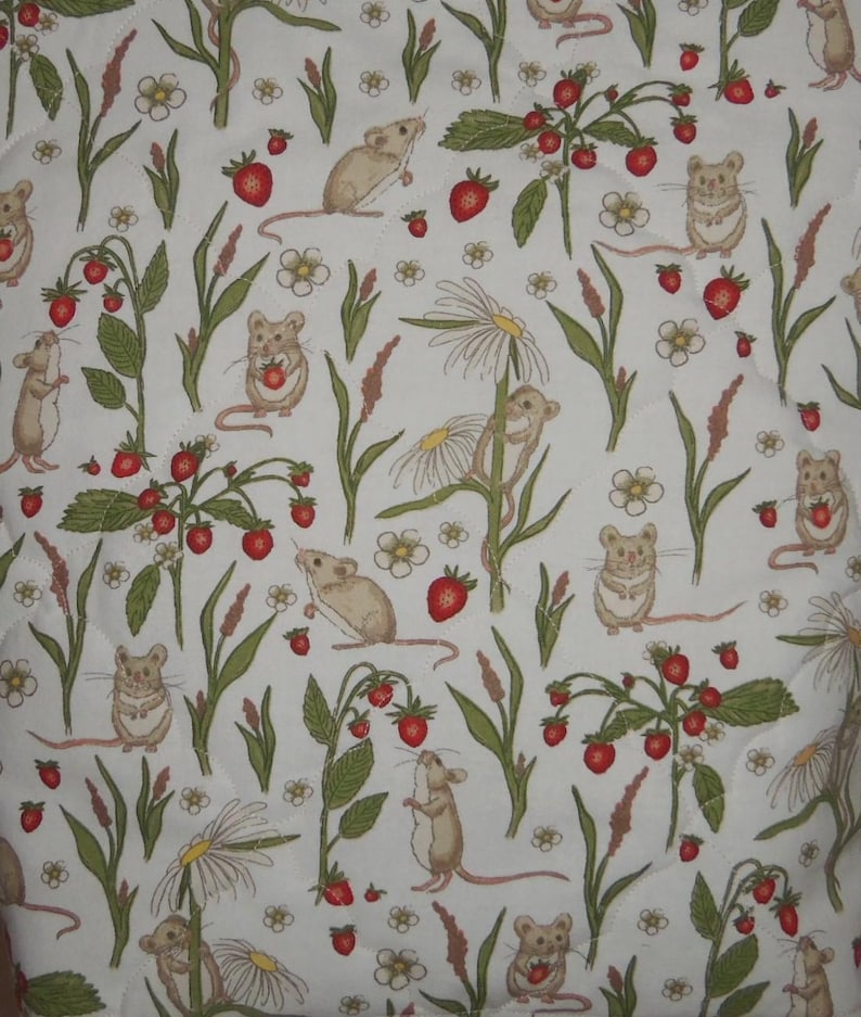May include: A white fabric featuring a repeating pattern of light brown mice, red strawberries, green leaves, and white daisy flowers. The quilted material displays various illustrations of mice interacting with the plants and fruit in a natural setting.