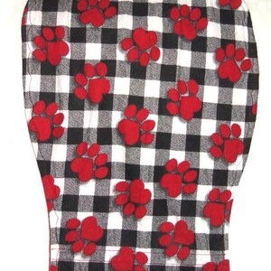 May include: Black and white checkered fabric with red paw prints. The fabric is a cotton blend and is perfect for quilting, crafts, and home decor.
