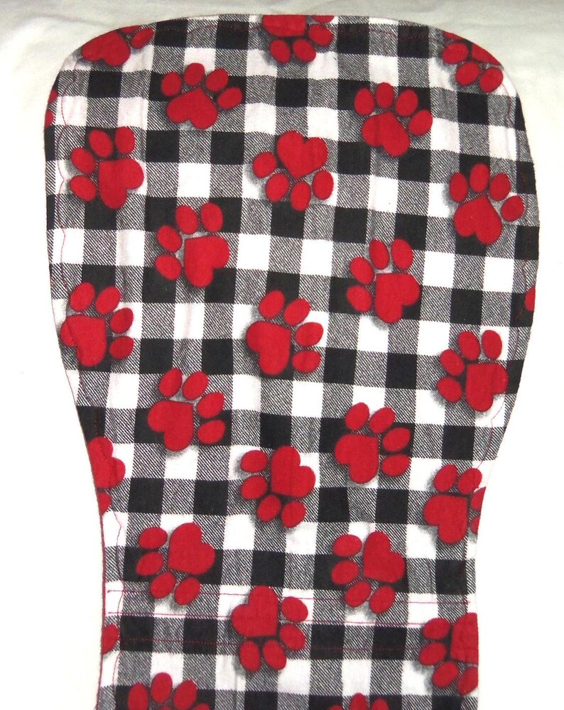 May include: Black and white checkered fabric with red paw prints. The fabric is a cotton blend and is perfect for quilting, crafts, and home decor.
