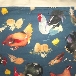 May include: A dark teal fabric featuring a watercolor design of chickens, roosters, chicks, eggs, and feathers. The chickens are in shades of brown, red, black, and white. The chicks are yellow, and the eggs are in nests.