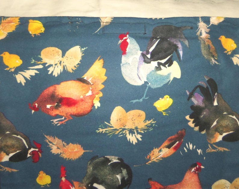 May include: A dark teal fabric featuring a watercolor design of chickens, roosters, chicks, eggs, and feathers. The chickens are in shades of brown, red, black, and white. The chicks are yellow, and the eggs are in nests.