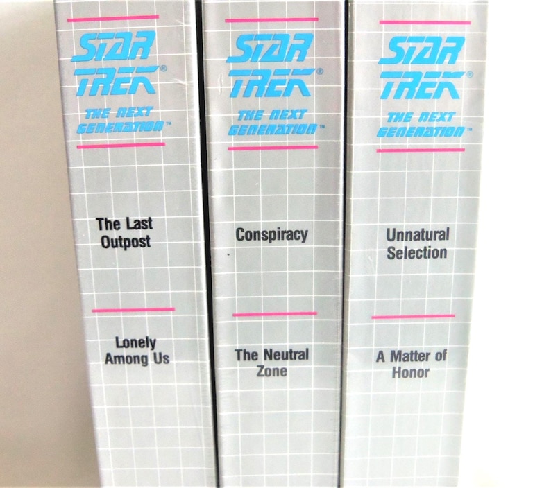 May include: Three Star Trek: The Next Generation VHS tapes with silver spines featuring a white grid pattern and bright blue text. The titles include The Last Outpost, Lonely Among Us, Conspiracy, The Neutral Zone, Unnatural Selection, and A Matter of Honor.