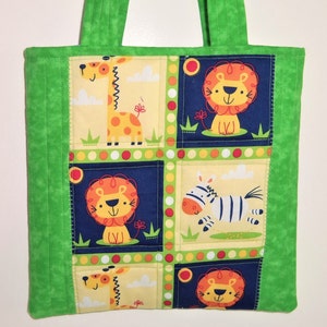 May include: A quilted tote bag featuring a vibrant green border and handles. The central panel displays a grid pattern with cartoon illustrations of giraffes, lions, and a zebra against yellow and dark blue backgrounds with colorful polka dots.