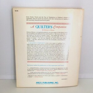 Puede incluir: La contraportada de un libro de tapa blanda titulado A Quilter's Companion de Dolores A. Hinson. La cubierta de color blanco hueso presenta texto impreso en negro que describe el contenido, incluyendo instrucciones para 200 colchas.