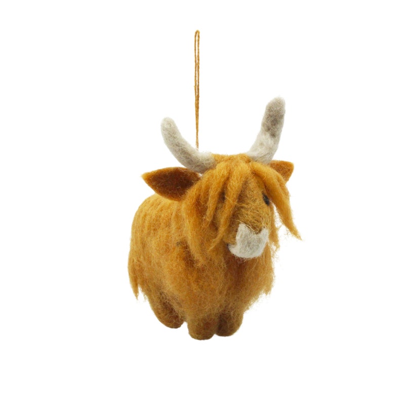 May include: A brown felt Highland Cow ornament with white horns and a white nose. The ornament has a string for hanging.