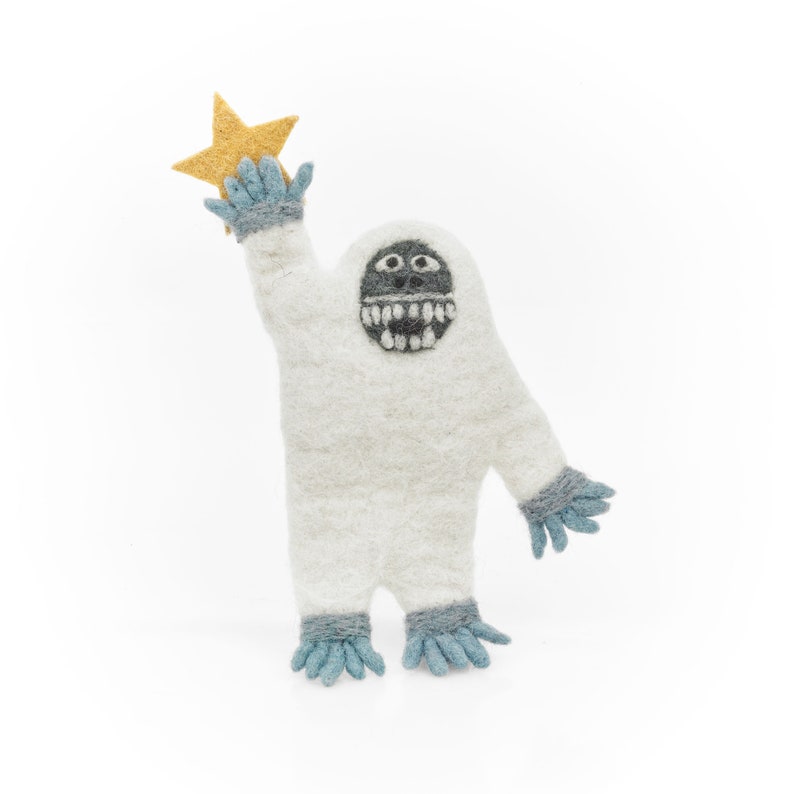 May include: A white felt snowman with a black face and teeth, wearing blue and gray mittens, holding a yellow felt star.