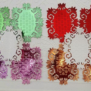 May include: A collection of decorative oval placemats in various colors. The placemats feature intricate, cut-out floral designs. Colors include green, red, white, purple, and gold. These placemats are ideal for adding a touch of elegance to any table setting.