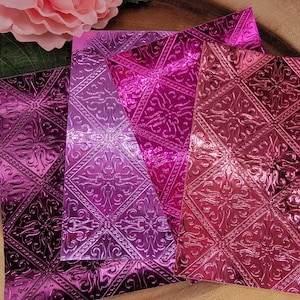May include: Three rectangular sheets with a metallic finish in shades of magenta, fuchsia, and deep purple. Each sheet features a repeating embossed pattern of squares containing intricate, symmetrical floral motifs with decorative borders.