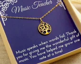 May include: A gold necklace with a tree of life pendant comes in a small blue box with a gold lid. The box has a white inscription that reads "Music Teacher" and a message that says "Music speaks when words fail. Thank you for giving me the wonderful gift of music. You have helped me grow one note at a time!"