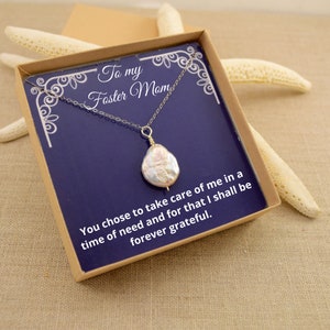 Op de afbeelding: Een zilveren ketting met een parel hanger in een cadeaudoos. De doos heeft een blauwe achtergrond met de tekst "To my Foster Mom You chose to take care of me in a time of need and for that I shall be forever grateful."