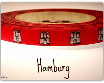 Könnte beinhalten: Rotes Band mit einem sich wiederholenden Muster aus schwarzen und weißen Stadttoren. Das Band ist aufgerollt und das Wort "Hamburg" ist in Schwarz unter dem Band geschrieben.