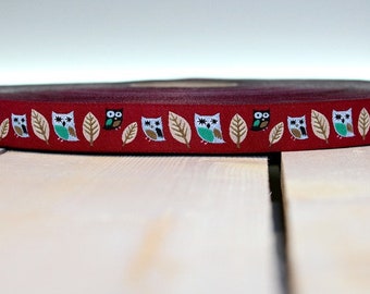 Könnte beinhalten: Rotes Band mit einem sich wiederholenden Muster aus weißen Eulen und braunen Blättern.