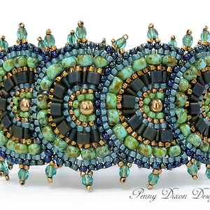 Puede incluir: Un brazalete de cuentas con un patrón geométrico en tonos de verde, azul y dorado. El brazalete tiene una franja de cuentas en la parte inferior.