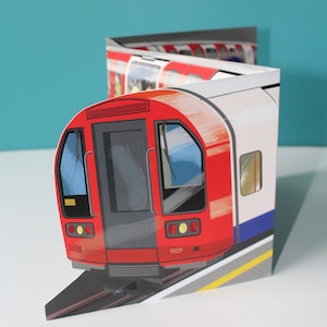 May include: A red and white London Underground train with the number 91129 on the side. The train is on a track with a yellow line down the center.