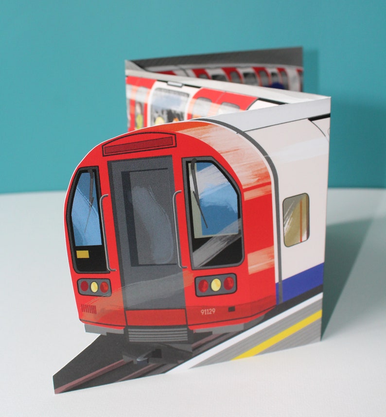 May include: A red and white London Underground train with the number 91129 on the side. The train is on a track with a yellow line down the center.