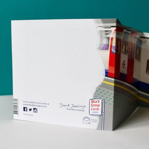 May include: A white card with a red, white, and blue London Underground train on the front. The back of the card has the text "Bus Stop Cards.com" and "David Jennings Illustration and design".