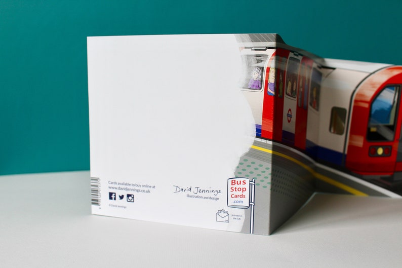 May include: A white card with a red, white, and blue London Underground train on the front. The back of the card has the text "Bus Stop Cards.com" and "David Jennings Illustration and design".