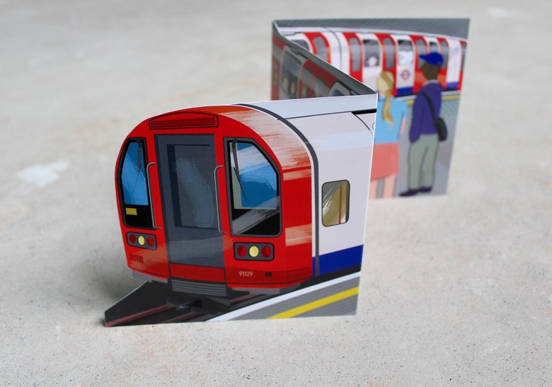 May include: A red and white London Underground train with a blue stripe. The train is on a track with a yellow line. There are people waiting on the platform.