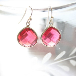以下が含まれることがあります： ピンクのファセットカットの宝石のドロップが付いたシルバーのドロップイヤリングのペア