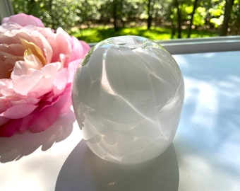 May include: White glass vase with a swirling, marbled pattern. The vase is round and has a small opening at the top.
