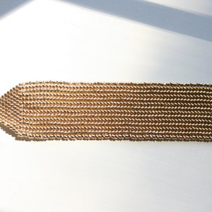 May include: A gold-toned chain bracelet with a toggle clasp. The bracelet is made of small, linked beads.