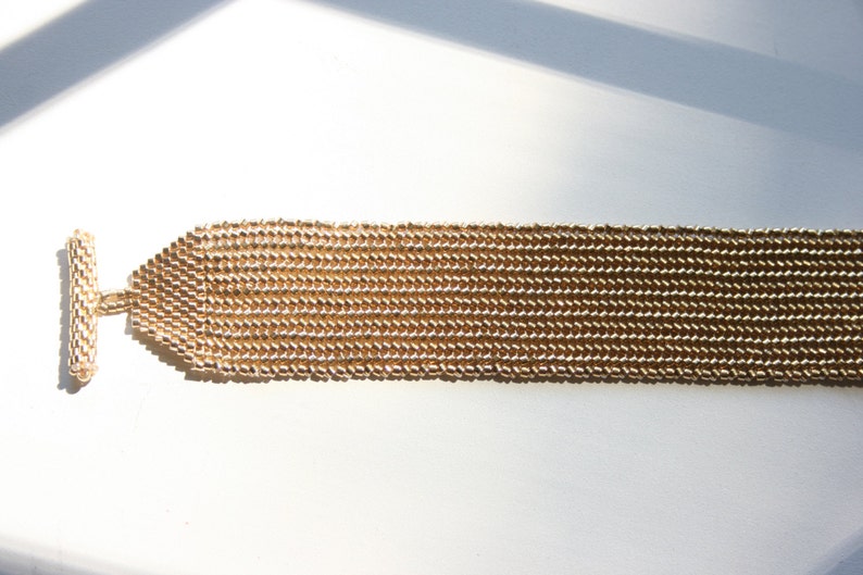 May include: A gold-toned chain bracelet with a toggle clasp. The bracelet is made of small, linked beads.