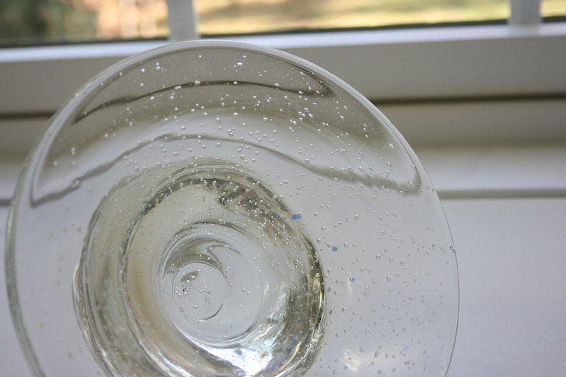 May include: A clear glass bowl with a textured surface. The bowl has a circular shape and a wide rim. The bowl is filled with small air bubbles.
