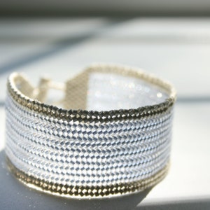 May include: A silver and gold beaded bracelet with a woven design.